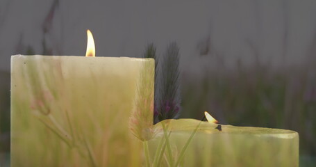 Image of lit candles over meadow and grass, copy space