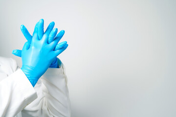 Doctor's hand in blue medical gloves holding an object on a white background