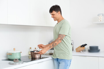 Young man cooking on stove in kitchen