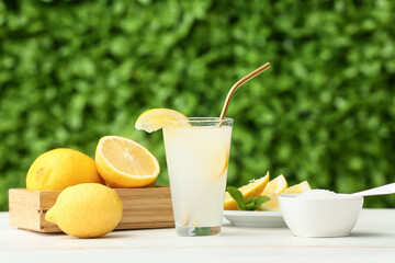 Glass of fresh lemonade with mint on white wooden table outdoors