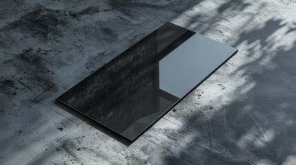 Sleek black smartphone on dark textured surface with sunlight casting shadows, showcasing modern design and reflective screen.