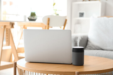 Air humidifier with laptop on table in living room, closeup