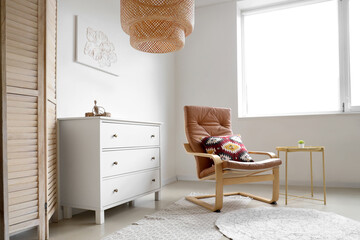 Interior of stylish living room with painting, commode and armchair