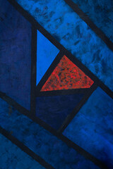 Pintura abstracta con triángulos en diferentes tonos azules con uno rojo en acrílico. 