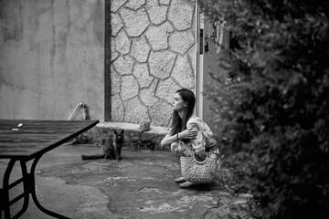 Lonely woman sitting on the ground next to a table and chair in black and white