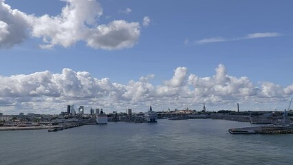 Tallinn.Estonia-July 21.2021: Awesome shot of Tallinn viewed from the sea. Amazing city architecture. Harbor. Cruise ships. Cloudy and blue sky. Panoramic. Camera slowly turning left.