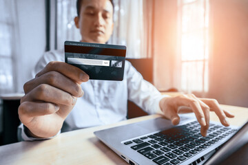 Young man use credit card for shopping payment online on laptop computer application or website....