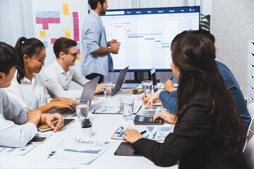 Project manager communicate and collaborate with team using project management software display on monitor, tracking progress of project task and making schedule plan at meeting table. Prudent
