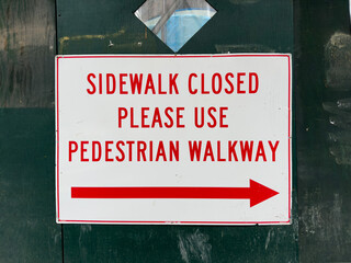 Sidewalk closed sign on a green wall