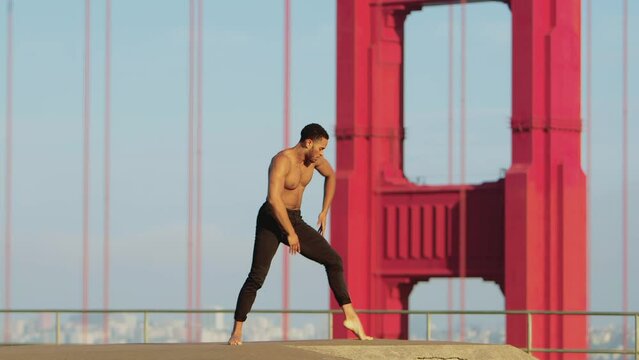 Male ballet dancer doing a choreographic dance move in front of the  of the Golden Gate Bridge in San Francisco, California, USA