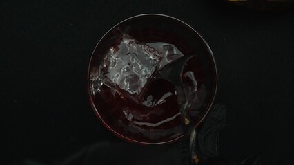 Top down view of bartender hand making and prepare Scarlet spritzer with black background. Close up...