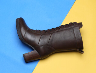 dark brown women boots on medium high heels on yellow blue background studio shot