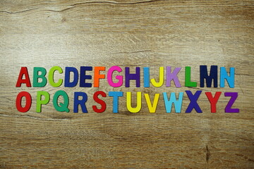 Fototapeta premium Colorful letterpress alphabet with space copy top view on wooden background