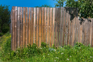 Fototapeta premium Photo of a wooden fence made of boards in a village garden.