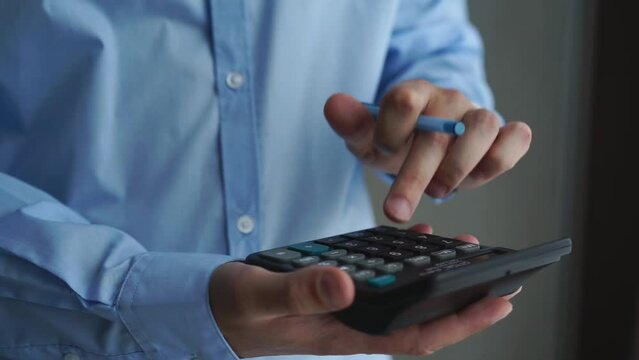 Close-up calculator.
A man in a blue shirt counts on a calculator.
Businessman counting money on a calculator
