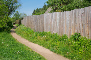 Fototapeta premium A path in the village along the fence.