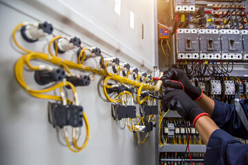 Electricity and electrical safety maintenance service system, Technician hand checking electric current voltage at circuit breaker terminal and cable wiring in main power distribution board.