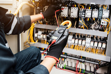 Electricity and electrical safety maintenance service system, Technician hand checking electric current voltage at circuit breaker terminal and cable wiring in main power distribution board.