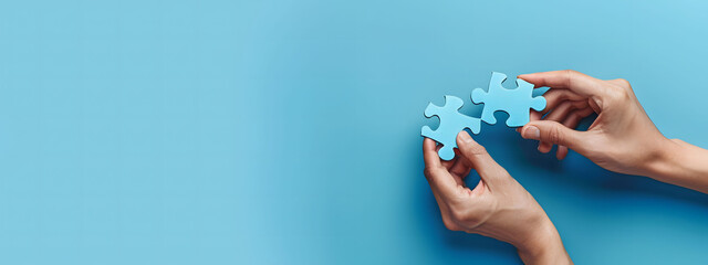 Two hands of business people connecting puzzle pieces on a blue background with copy space, symbolizing collaboration and teamwork. Background for business solutions, success, and strategy.