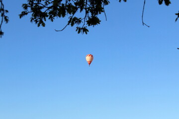 A hot air balloon with a basket flies in the evening sky.