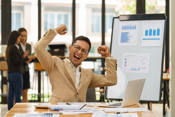 Asian businessman raising his arm to celebrate success.