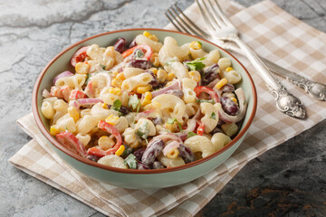 Southwestern elbow pasta salad filled with fresh veggies, red beans, and a zesty dressing close up on the bowl on the table. Horizontal