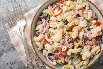 Homemade Southwestern elbow pasta salad with fresh vegetables and creamy dressing close up on the bowl on the table. Horizontal top view from above