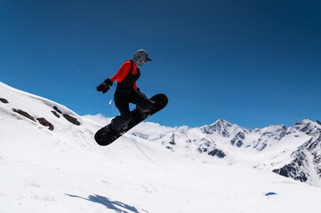 snowboarder in bright sportswear makes a trick against the backdrop of beautiful mountains