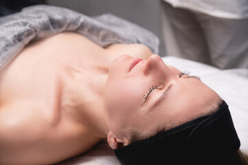 Close-up photo of a young woman with her eyes closed. The patient lies and waits for a dermatologist or cosmetologist, the beginning or end of care procedures