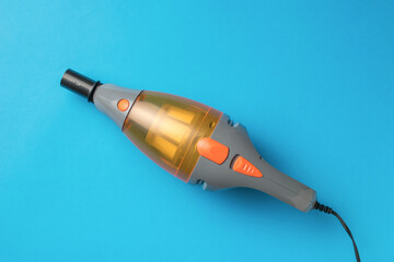 Handheld Electric Vacuum Cleaner on Blue Background - Modern Compact Cleaning Device