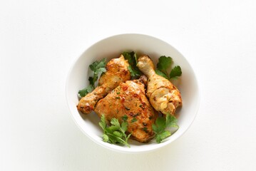 Oven baked chicken meat with greens in bowl on white background