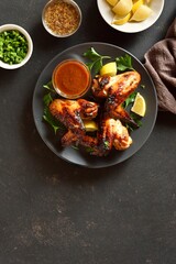 Bbq chicken wings on plate over dark stone background with copy space