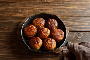 Minced pork and beef cutlets in cast iron pan on wooden background