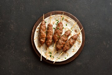 Grilled lula kebab on flat bread on wooden platter