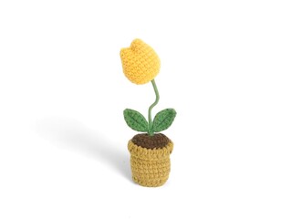 A knitted doll in the shape of a yellow flower in a pot on a white background