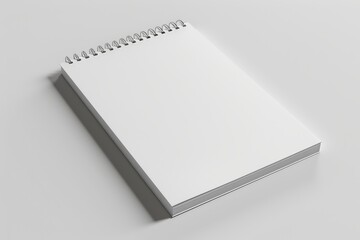 A white spiral bound notebook is laying flat on a white surface, the notebook is closed and the binding is visible