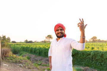 Young indian farmer standing at agriculture field 