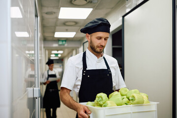 Male cook carrying fresh vegetables from  pantry.