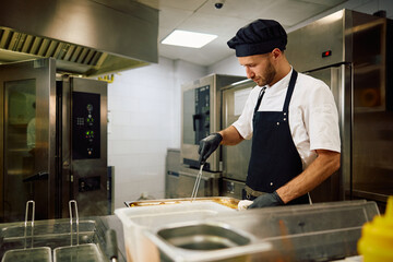 Mid adult chef preparing food in  restaurant.