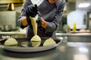 Close up of chef using icing bag while decorating  plate.