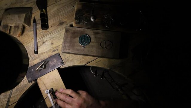  a jeweler's hand saws off excess metal on the work table