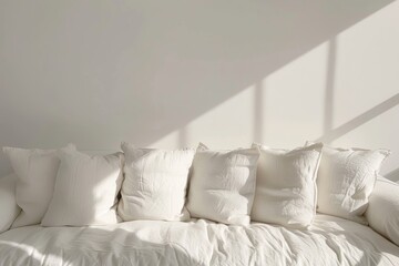 A close-up shot of a white couch with several pillows. Sunlight streams through a window, casting shadows on the cushions and bedding