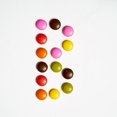 Colored chocolate coated candy alphabet on white background. B