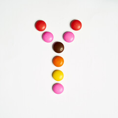 Colored chocolate coated candy alphabet on white background. y