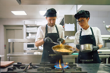 Chefs cooperating while preparing pasta in  kitchen.
