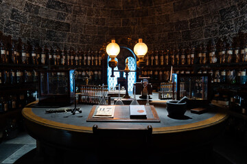 Naklejka premium JAPAN - Nov 13, 2023: Vintage apothecary room with shelves lined of potion bottle laboratory equipment and book on the table at Warner Bros. Studio Tour Tokyo, The Making of Harry Potter