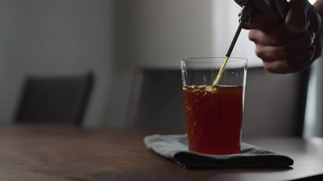 Slow motion pour nitro coffe in tumbler glass on wood table