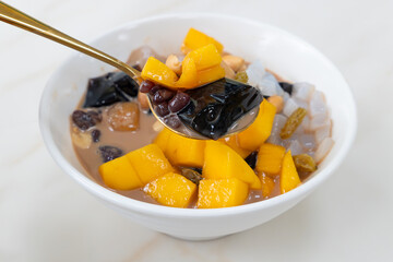 angle view bowl of milktea flavor syrup mixed with grass jelly and mangoes and peach gum and tapiocas and red beans and guiling jelly etc. at horizontal composition