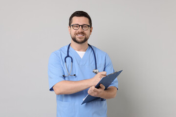 Smiling doctor with clipboard on light grey background
