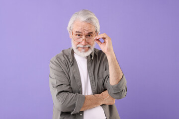 Portrait of stylish grandpa with glasses on purple background